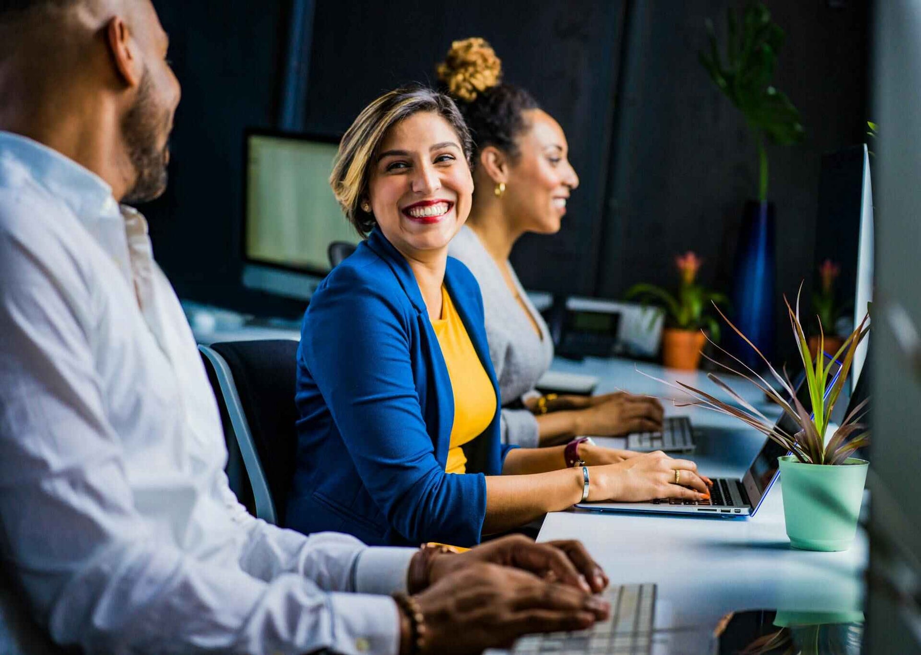 Best Gift Ideas for Sending Your Work Anniversary Wishes; work anniversary gift idea; smiling woman at work; corporate gift ideas