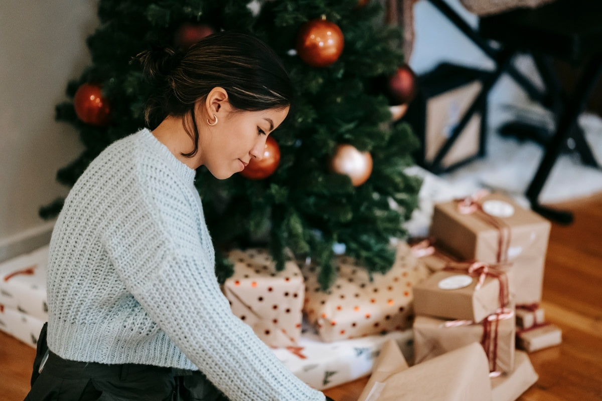 woman with pile of present boxes against Christmas tree