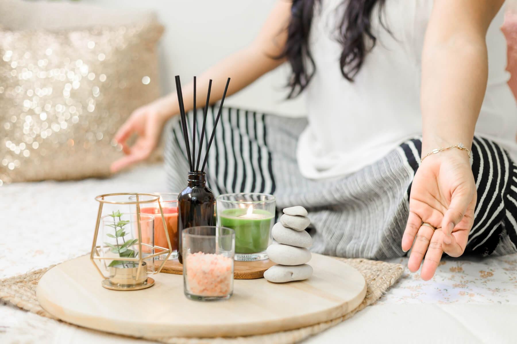 woman meditating in front of candles with different fragrance notes