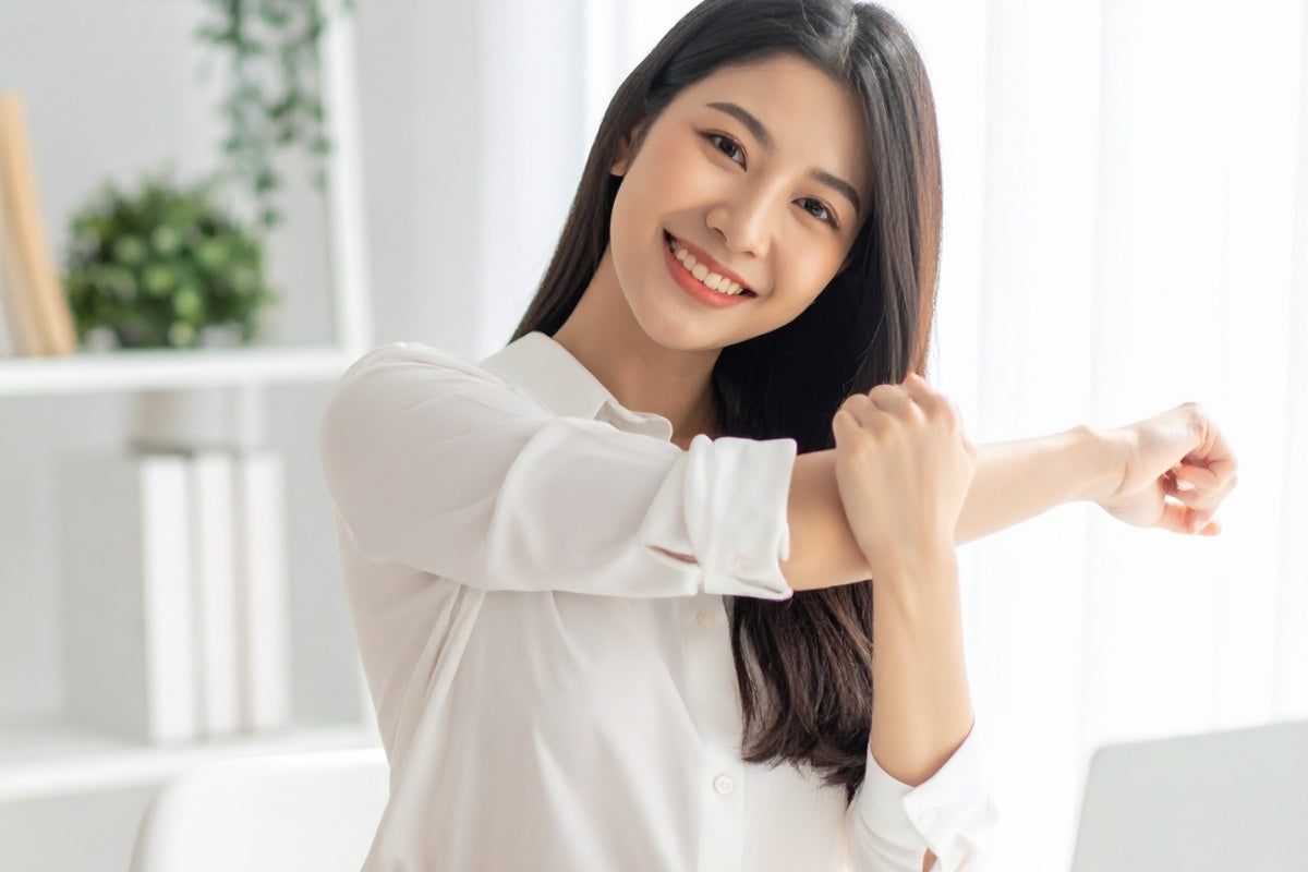Asian Woman Stretching at Desk in Office Photgraph