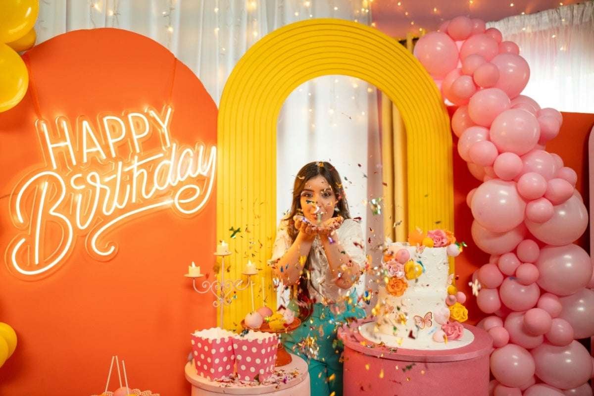 birthday celebrant Throwing Confetti between Birthday Decorations 