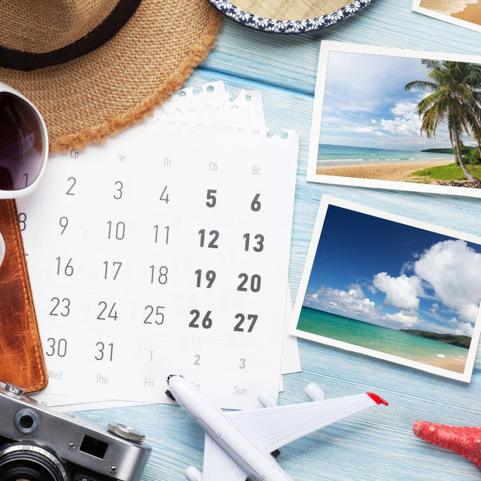 planning a vacation with sunglasses, calendar, camera and toy airplane