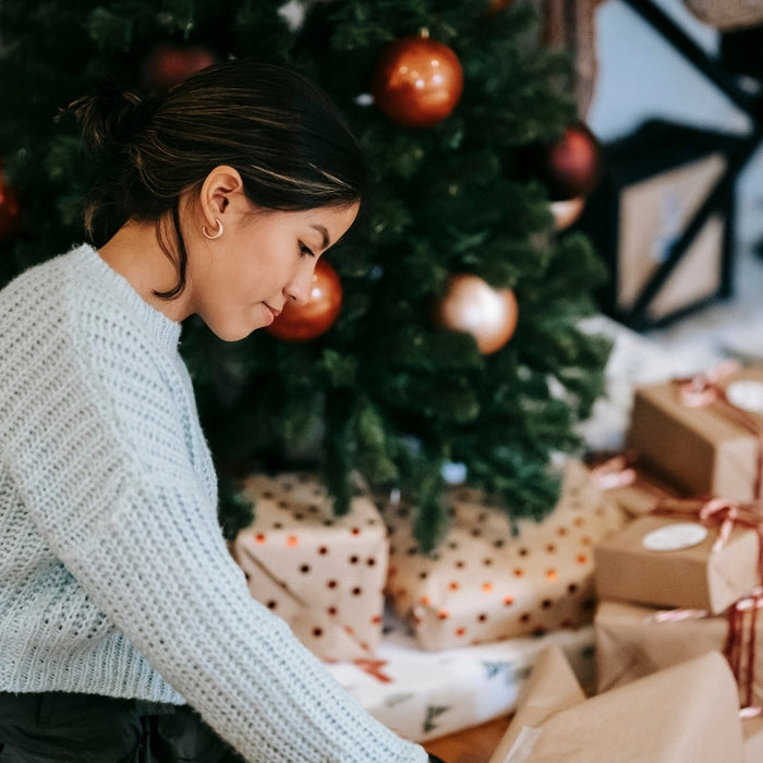  woman with pile of present boxes against Christmas tree